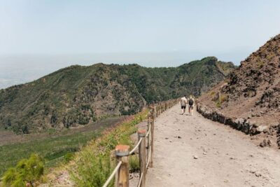 A walker on the black ash slopes of Mount Etna below a rising plume